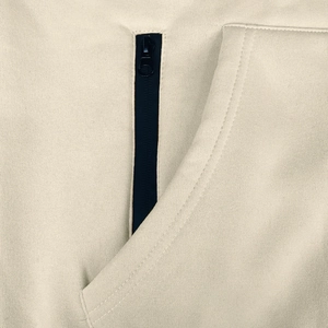 Detail of high-density knit fabric and vertical black zipper pocket on beige hoodie