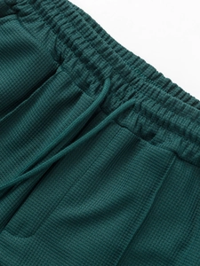 Detail of dark green waffle knit shorts featuring elastic waistband and drawstring