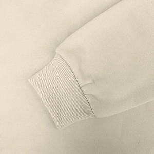 Detailed macro view of the beige fleece hoodie ribbed cuffs and high-quality knit texture