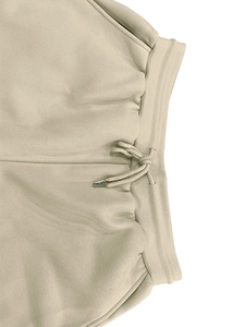 Detail of beige fleece joggers featuring elastic waist with drawstring and metal tips