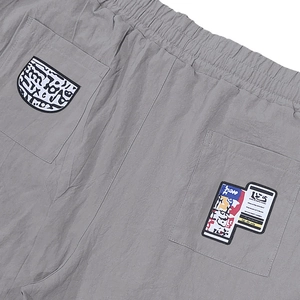 Detail view of grey linen trousers featuring elastic waistband and graphic patchwork pockets