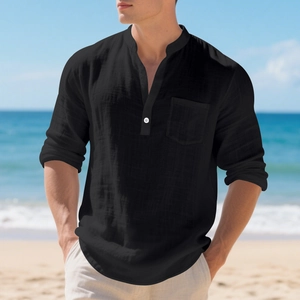 Close-up of black linen Henley shirt texture with white button and pocket detail on beach