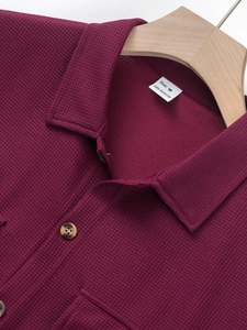 Detailed macro view of burgundy waffle texture shirt with collar label and wood-style buttons