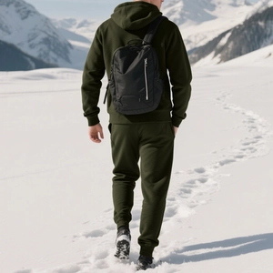 Detail of green fleece hoodie set and black nylon backpack in snowy mountain scenery