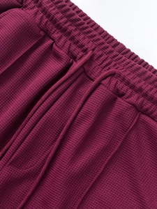 Detail of burgundy waffle knit shorts with elastic waistband and matching drawstring