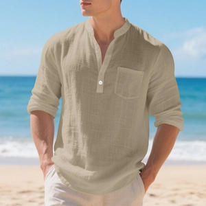 Detailed texture of men's khaki linen Henley shirt against a scenic beach backdrop