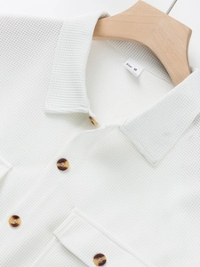 Close-up of white waffle knit fabric texture with brown buttons and size M tag