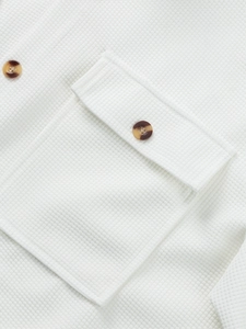 Detailed close-up of waffle-knit fabric shirt with flap pocket and marble button