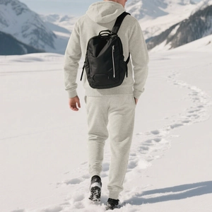 Close-up of black waterproof nylon travel backpack with side zipper pocket in snowy mountains