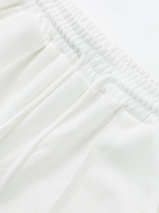 Close-up of white waffle knit fabric texture on shorts with elastic drawstring waist
