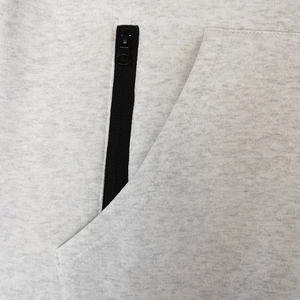 Detail of light grey fleece hoodie featuring a black zipper pocket and reinforced stitching