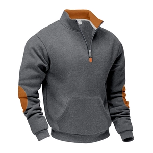 Detail van een donkergrijze hoodie met oranje elleboogstukken en ritsaccenten