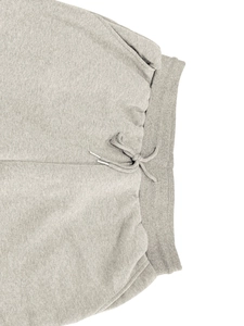 Detail of grey fleece sweatpants featuring a ribbed elastic waistband and drawstring cords