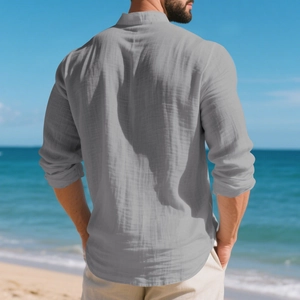 Back view of a grey linen henley shirt for men in a scenic beach setting with rolled sleeves
