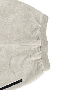 Detail of grey athletic pants showing elastic ribbed waistband and black zipper pocket