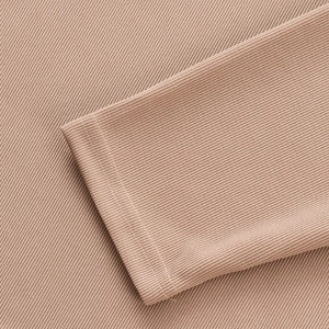 Gros plan du poignet d'un polo kaki montrant les coutures et la texture du tissu côtelé
