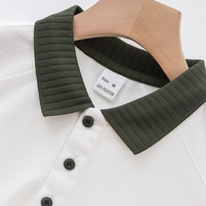 Détail d'un polo blanc en maille côtelée avec col vert foncé contrasté et des boutons