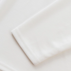 Gros plan sur la texture du tricot blanc côtelé et l'ourlet à double couture du polo