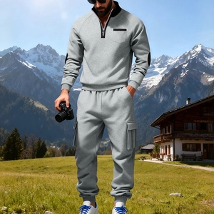 Nahaufnahme des grauen Sweatshirts mit schwarzem Stehkragen und Cargohose vor Gebirgshintergrund