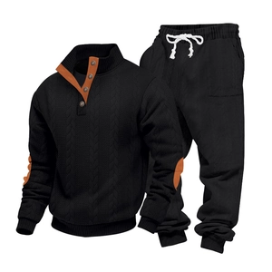 Detailoverzicht van zwarte hoodie-set met oranje kraagvoering en elleboogstukken in textuur