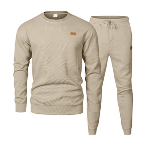 Detail of men's beige tracksuit with textured geometric pattern and leather patch accents
