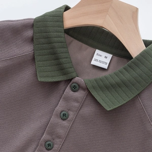Détail du col contrasté, de la texture côtelée et de l'étiquette taille M du polo