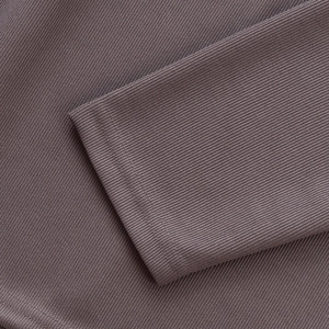 Détail macro des poignets et de l'ourlet en maille côtelée de ce polo à manches longues