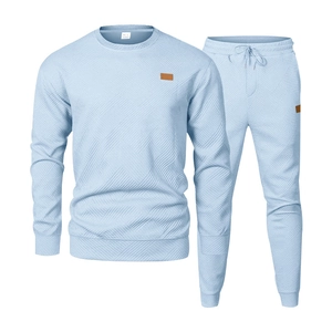 Detail of light blue men's tracksuit showing geometric knitted texture and leather patch
