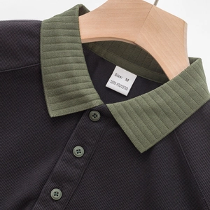 Détail du col côtelé vert olive et des boutons sur un polo en maille bleu marine