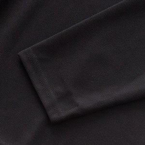 Gros plan de la texture à côtes verticales et couture du poignet sur polo en tricot