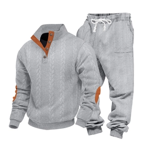 Detail van grijs gebreid trainingspak met oranje contrastpatches en trekkoord in taille