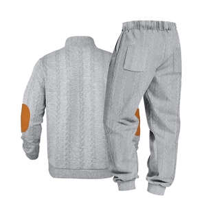 Detail van lichtgrijze gebreide trainingspak met kabelpatroon en bruine elleboogpatches