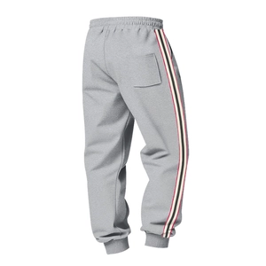 Detail of grey joggers featuring drawstring waist and tricolor side stripes for men