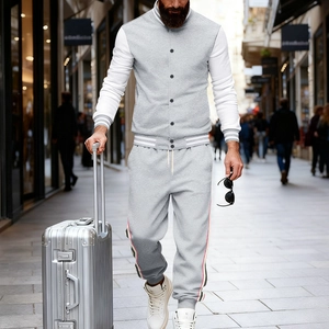 Détail de la veste de baseball grise et du jogging à rayures sur un fond de rue