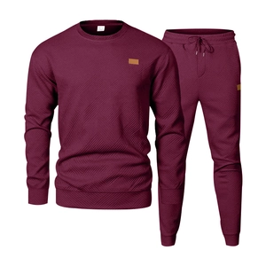 Detail of burgundy men's tracksuit set featuring a textured diamond knit pattern and leather patch