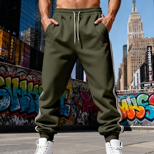 Detail of dark green joggers featuring white side stripes and adjustable drawstring waist