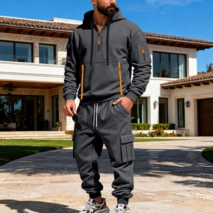 Detailed view of dark grey tracksuit with orange zippers and cargo pockets on hood and pants
