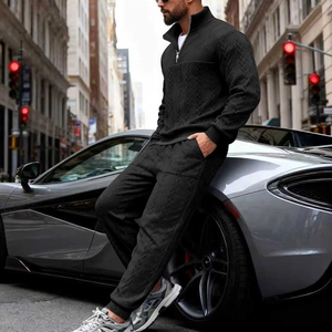 Detail of men's black knit tracksuit with textured pattern next to a luxury car