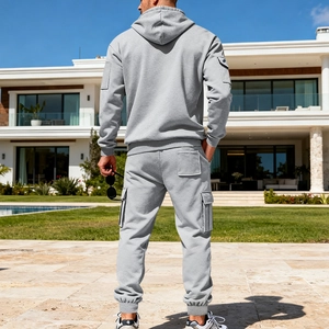 Rear view of grey men's tracksuit featuring hoodie and cargo joggers in a luxury outdoor setting