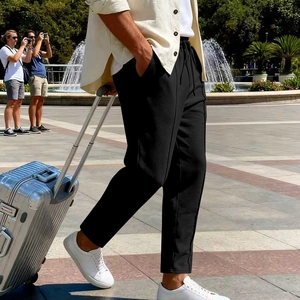 Men's black casual twill trousers with drawstring waist shown in an outdoor travel setting