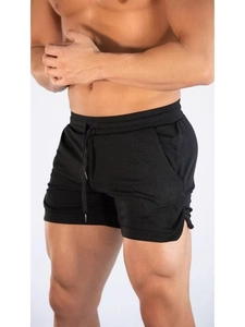 Detail view of men's black athletic shorts featuring side slits and drawstring waist