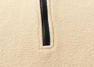 Close-up of durable black plastic zipper and sand beige polar fleece fabric texture