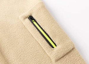 Close-up of beige fleece jacket pocket with black zipper and neon green ribbon detail