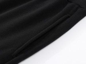 Detail view of black fleece sweatpants showing ribbed waist and side pocket stitching