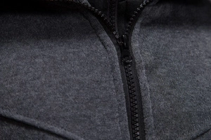 Detailaufnahme von dunkelgrauem Strickstoff mit schwarzem Metallreißverschluss am Kragen
