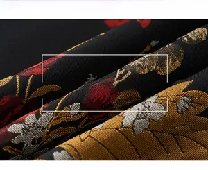 Macro shot of vintage floral jacquard fabric with gold and red embroidery on black background