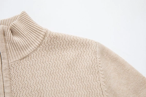 Detailed view of beige knit sweater showing stand collar and textured chevron pattern