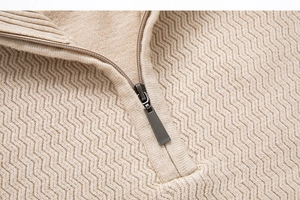 Close-up of knit texture and metal half-zipper on beige stand collar sweater
