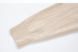 Detailed close-up of ribbed cuffs and high-density knit texture on men's beige sweater