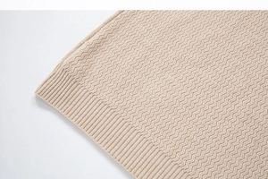 Detail of apricot knit sweater featuring textured wave patterns and elastic ribbed cuffs